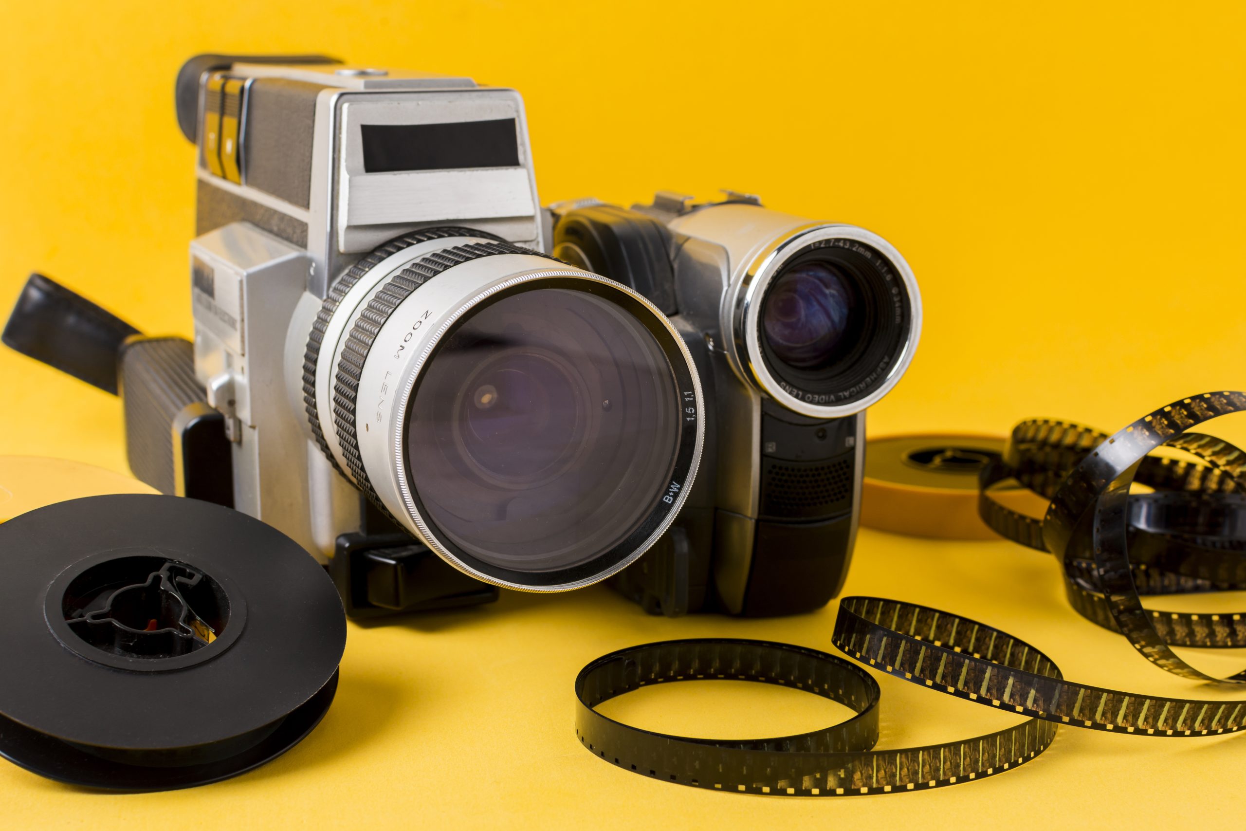 modern-camera-film-reel-film-strips-yellow-background